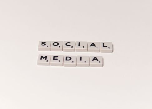 Scrabble tiles spelling 'social media' on a white background, representing digital communication concepts.